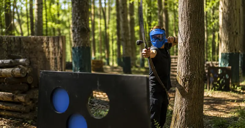 Archer masqué visant une cible en bois sur le terrain forestier de Wavre