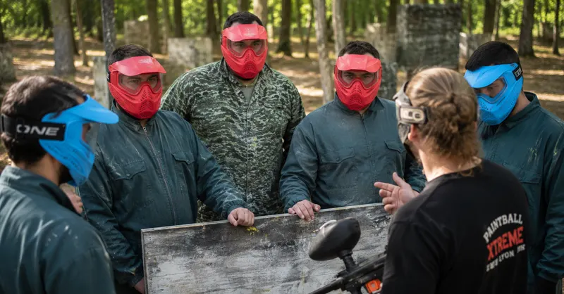 Joueurs en combinaison et masques recevant les consignes avant leur première partie de paintball