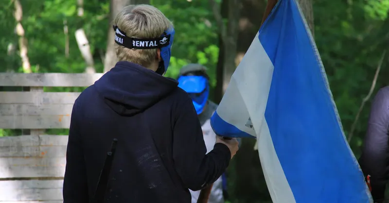 Joueur ramenant le drapeau de son équipe pendant un scénario de capture du drapeau en forêt